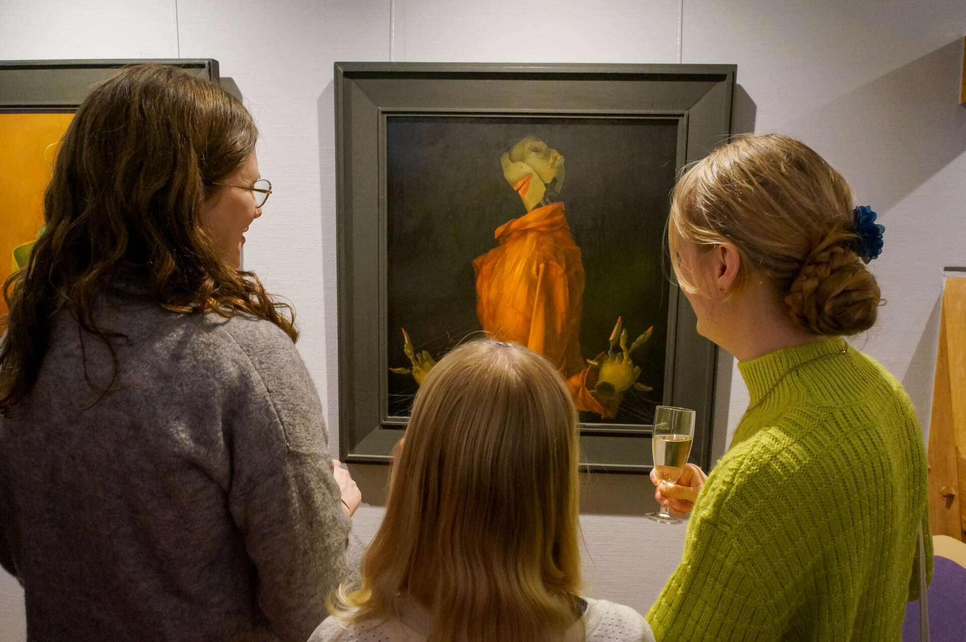 Drei Personen betrachten ein Bild in der Ausstellung.