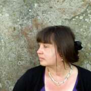 Ein Bild von Andrea Lydia Stenzel, sie blickt nach links, und die Hälfte ihres Gesichts ist sichtbar.